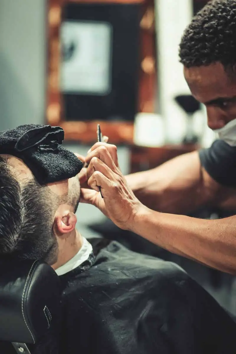 Barber shaves a customer with a straight razor